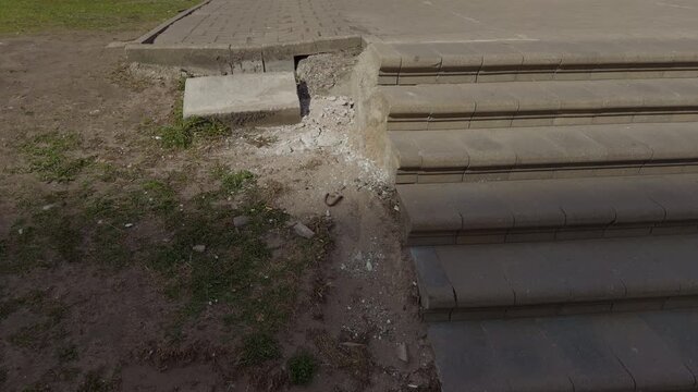 Cracked exterior steps with missing corner and loose rubble creating accessibility hazard, chipped edges and eroded concrete emphasize safety risk and need for repair in outdoor entrance