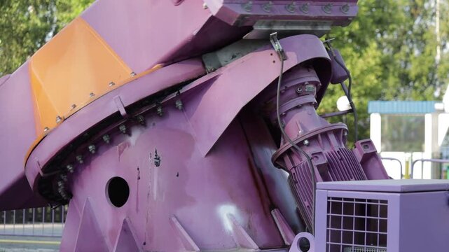Close-up of a robust mechanical drive system in vivid purple hue, showcasing the raw power behind an amusement ride's motion. The intricate assembly of gears and motor conveys a sense of controlled st
