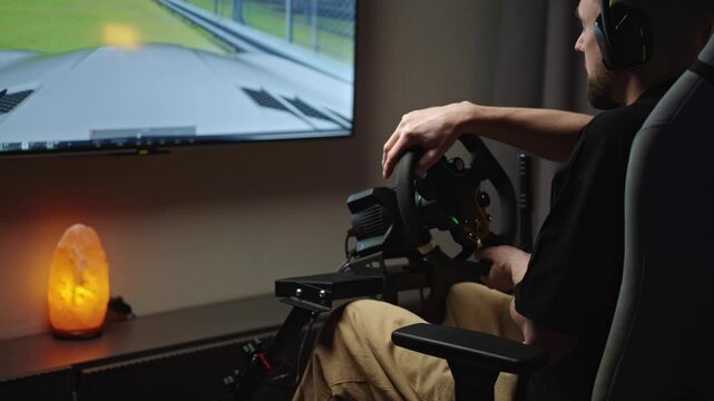 Man removing headset after virtual crash on racing simulator, quiet home studio with monitor and lamp, frustrated streamer pausing