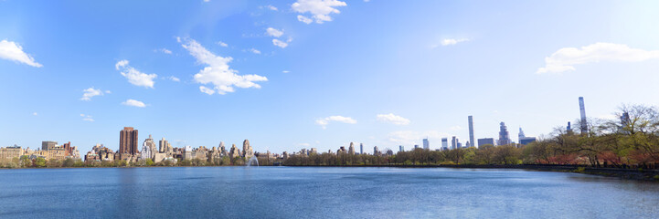 Obraz premium A panoramic daytime view of the Jacqueline Kennedy Onassis Reservoir in Central Park, New York City, featuring the urban skyline.