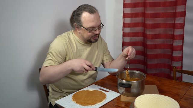 Man spread wafer cakes with condensed milk. Simple cake. Sweet food at home. Hands spread cream with knife.