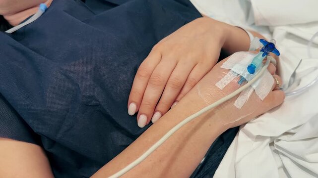 Close-up of an intravenous drip in the hand of a patient lies on bed in the hospital. High quality 4k footage
