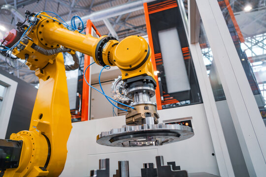 Industrial robotic arm holding metal gear component in automated factory cell.