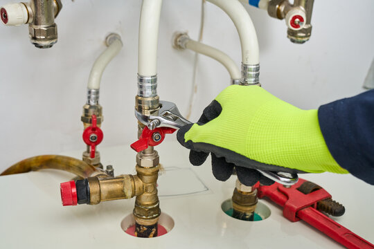 Man repair gas boiler with wrenches, gas heating boiler service at home