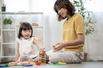 Naklejka premium Happy Asia mother play and learn toy blocks with the little girl. Funny family is happy and excited in the house. Mother and daughter having fun spending time together. Holiday, Activity, development