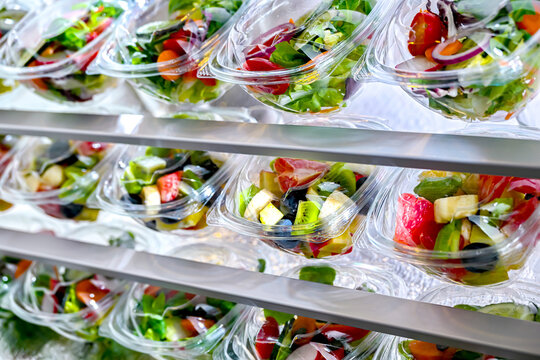 Plastic boxes with pre-packaged fruit and vegetable salads, put up for sale in a commercial refrigerator