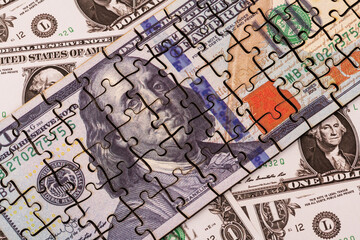 Fototapeta premium A puzzle-shaped $100 bill against a backdrop of $1 bills