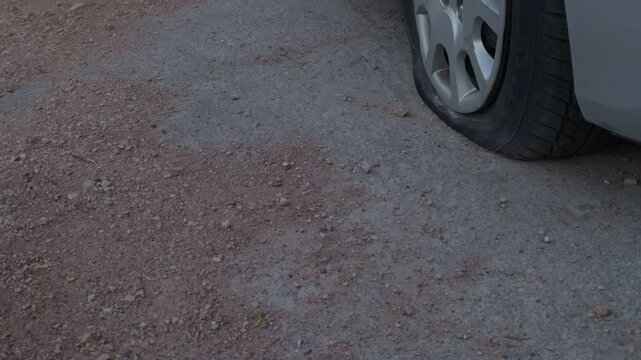 Expert view of car rim and tread patterns. Zoomedin image showing rocky terrain beneath car wheel. Detailed closeup highlighting tire tread and rim against rough gravel surface