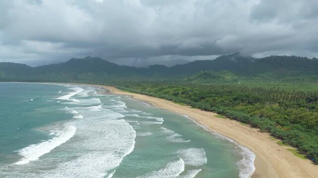 Aerial view of beautiful tropical ocean waves crashing on a sandy beach in java