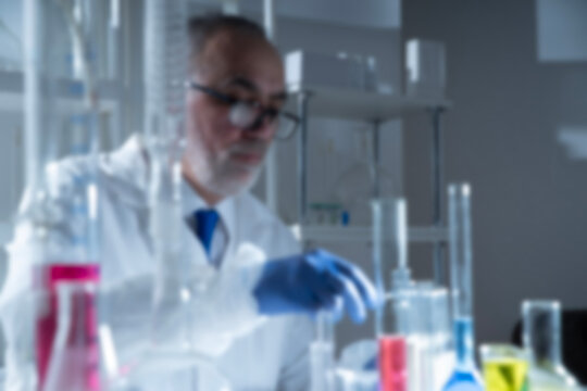 Blurred background scientific concept with senior scientist working in a modern laboratory, chemical samples, glass flasks, test tubes. Chemistry expertise, scientific methodology, laboratory science