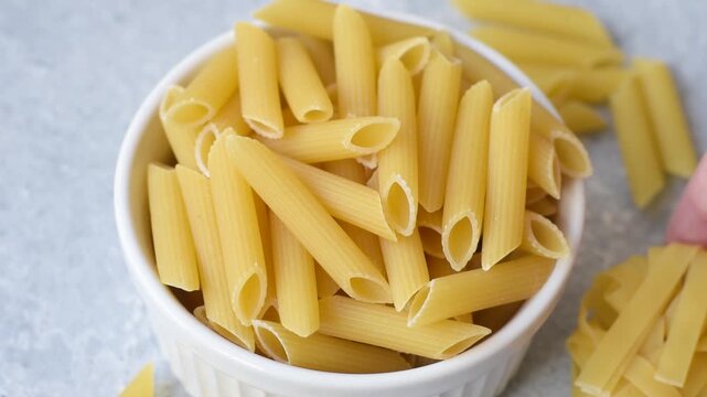 Italian uncooked dry penne regate pasta ready for cooking. Dry penne pasta as a food background for your design.