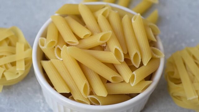 Italian uncooked dry penne regate pasta ready for cooking. Dry penne pasta as a food background for your design.