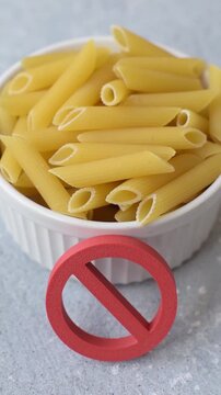 Italian uncooked dry penne regatta pasta with a gluten prohibition sign. The gluten prohibition sign as a background for your design.