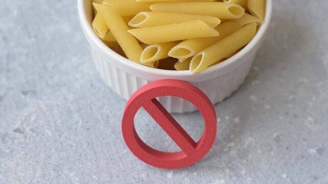 Italian uncooked dry penne regatta pasta with a gluten prohibition sign. The gluten prohibition sign as a background for your design.