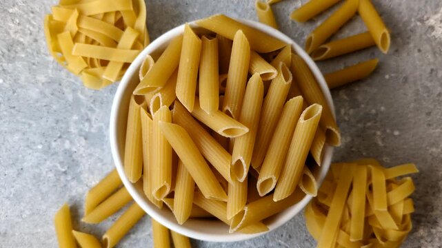 Italian uncooked dry penne regate pasta ready for cooking. Dry penne pasta as a food background for your design.