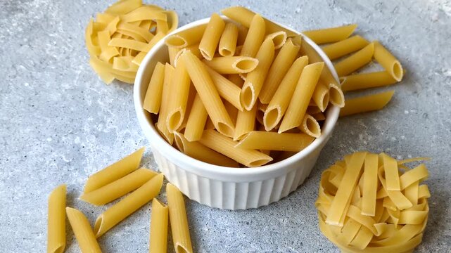 Italian uncooked dry penne regate pasta ready for cooking. Dry penne pasta as a food background for your design.