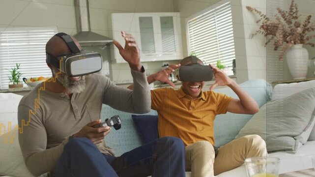 Father and son playing VR gaming, father activating controller, son cheering then removing headsets