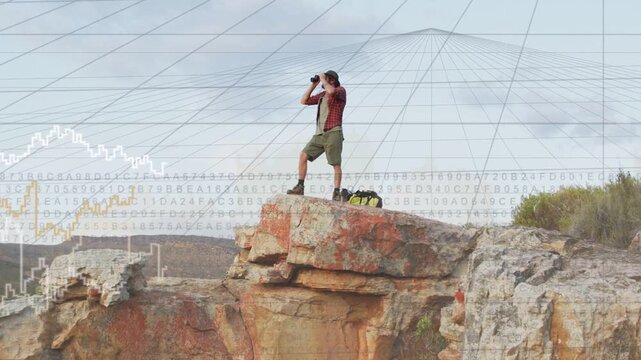 Male hiker on rock ledge shifting and scanning horizon with binoculars causing tech overlay mapping