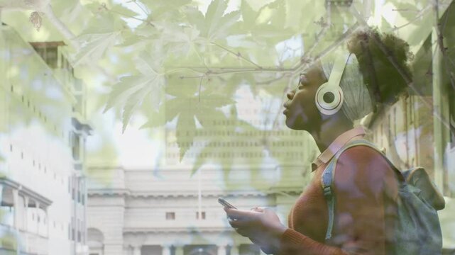 Woman on campus reading phone, raising head checking facade, tuning headset, leaf overlay drifting