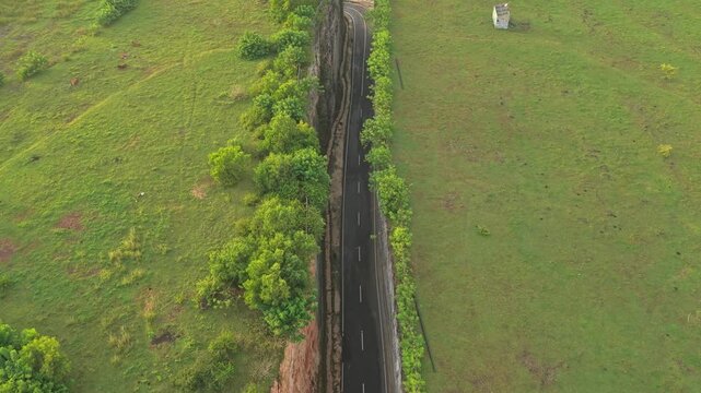 Aerial top down view of a road cut through a cliff to the ocean, Tanah barak, Bali
