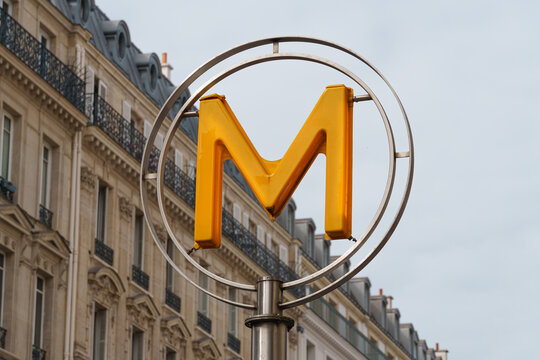 Paris Metro sign with yellow M symbol against classic Haussmann building facade