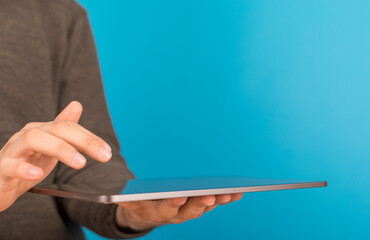 Person using a tablet device, interacting with the screen. Blue background, technology concept. © vegefox.com