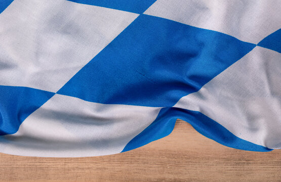 Close up of a Bavarian flag fabric, on a wooden surface, with traditional blue and white diamond pat