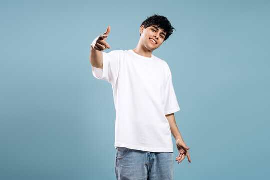 Smiling young man in blank white oversized t shirt pointing at camera