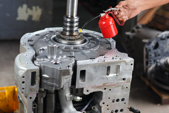​Professional technician manually assembling a clutch pack by inserting a friction disc into an automatic transmission housing during a gearbox rebuild.