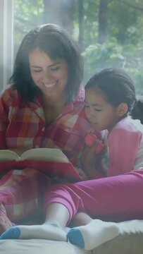Vertical video: Mom starting reading by window leading child leaning and teaching with book and toy