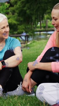Vertical video: Group sitting on lawn, camera panning causing floating social icons for sharing