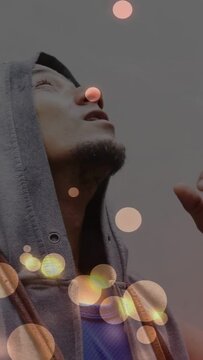 Vertical video: Man gazing up as warm bokeh brightening leading to hand rubbing eye for marketing