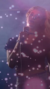 Vertical video: Female singer holding wired mic, singing for music, bokeh drifting over face