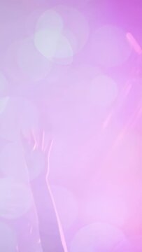 Vertical video: Single arm rising sparking hands joining palms opening under purple lights cheering