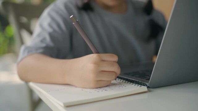 Child Engaged in Homework, Writing in Notebook, Using a Laptop, Focused on Learning, Cozy Study Environment, Educational Activities, Indoor Study Space