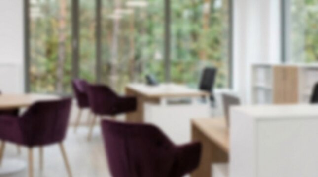 Stylish contemporary workspace softly blurred for depth features modern desks surrounded by striking deep plum purple velvet office chairs.