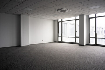 Naklejka premium Spacious empty office interior with gray carpet and large windows