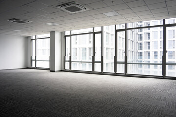 Naklejka premium Spacious modern office interior with floor-to-ceiling windows and abundant natural light