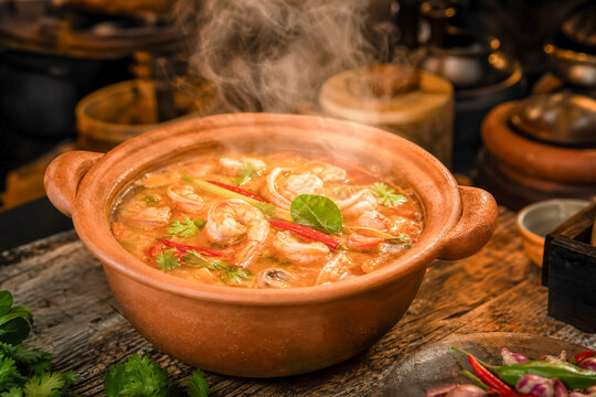Cooking shrimp soup in a clay pot with herbs and spices during the evening at a kitchen