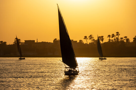 Traditional Egyptian feluccas sailing on the Nile River at sunset