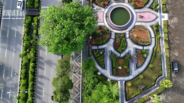 A view from above of an urban boulevard with a green median, traffic, and pedestrians along the sidewalk in a park in the city of Pontianak, Indonesia.