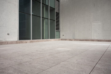 Naklejka premium Modern architectural concrete wall with glass curtain wall and empty paved ground space