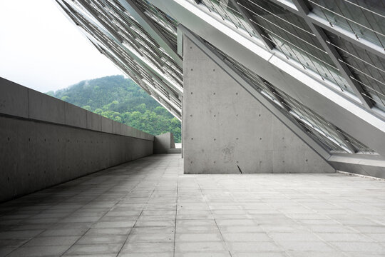 Modern architectural corridor with sloped concrete roof glass panels and mountain view in background