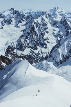 Majestic panoramic view of skiers descending the snow-covered Ar&ecirc;te ridge at Aiguille du Midi in the Mont Blanc massif. 