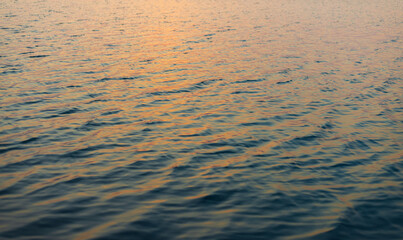 Purple and Blue Water Ripples Background at Sunset,Beautiful abstract texture of water surface with small ripples reflecting the purple and pink colors of the sunset sky, creating a serene and calm. © banjongseal324