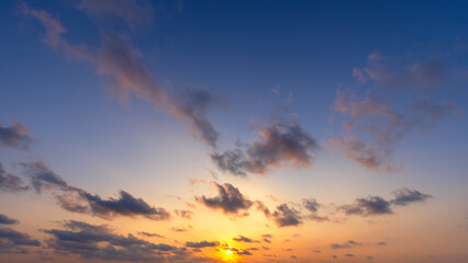 Fototapeta premium Beautiful golden sunset with orange sky and blue gradient clouds,A breathtaking panoramic view of the evening sky during sunset, featuring a vibrant orange horizon, soft golden light, and scattered.