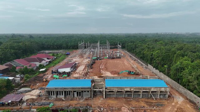 An aerial view of the construction of a substation in a tropical oil palm plantation, showing transformers and infrastructure.