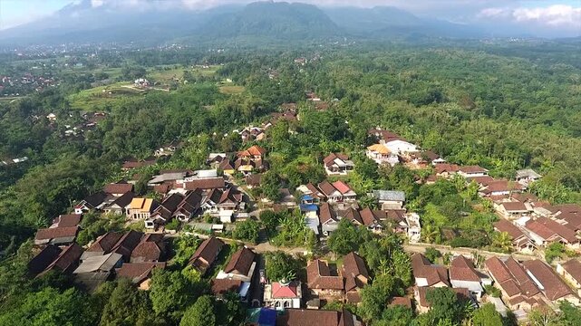 Aerial view of a traditional Indonesian village nestled at the foot of a majestic mountain.