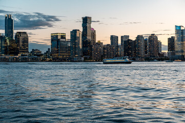 Obraz premium Jersey City skyline and Goldman Sachs Tower at sunset dusk. View of the Jersey City waterfront and financial district skyscrapers from the Hudson River during twilight.