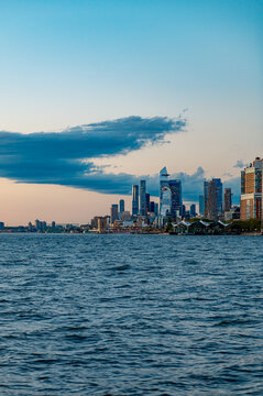 Hudson Yards skyline and West Side Manhattan from Hudson River. Wide angle view of the Hudson Yards development and Midtown West skyline under a large cloud at sunset.